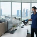 Commercial disinfection technician sanitizing a corporate office in Singapore with an electrostatic sprayer to prevent seasonal flu outbreaks.